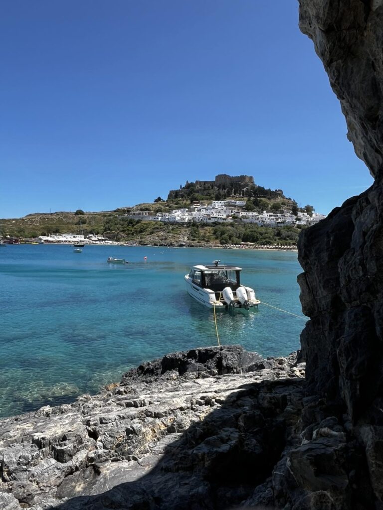 My dolce vita yacht is anchored in clear blue water of Lindos bay. In the background the all white scenic town of Lindos